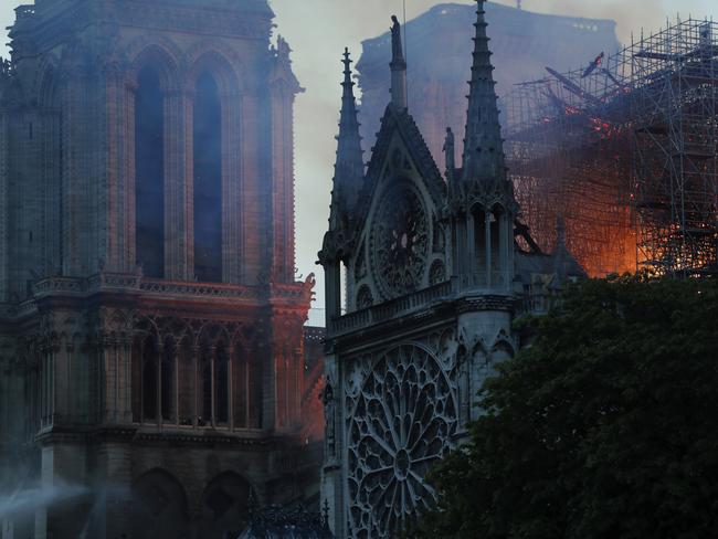 Firefighters tackle the blaze as flames and smoke rise from Notre Dame cathedral as it burns in Paris, Monday, April 15, 2019. Massive plumes of yellow brown smoke is filling the air above Notre Dame Cathedral and ash is falling on tourists and others around the island that marks the center of Paris. (AP Photo/Thibault Camus)