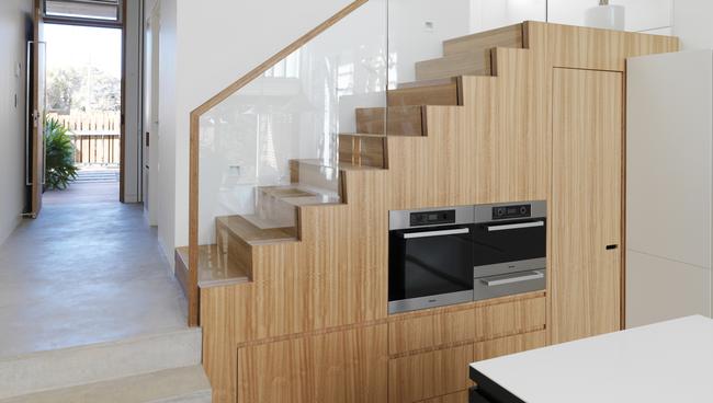 Kitchen appliances, storage space and a pantry fit seamlessly under the stairs in this house designed by Simon Anderson Architecture.