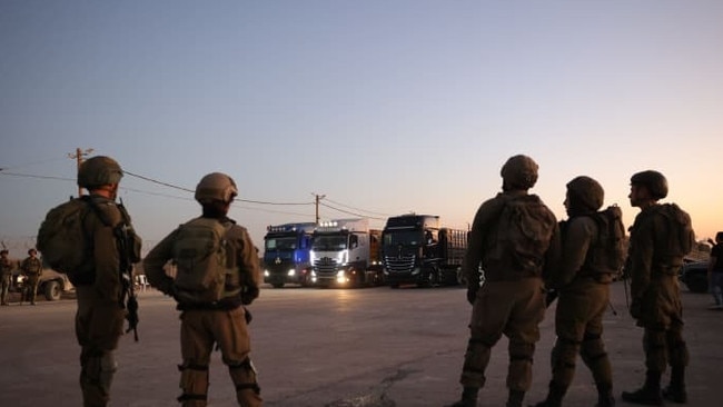 Israeli soldiers face Jordanian aid trucks arriving at a Gaza border crossing on Monday. After two weeks of no aid entering the Gaza Strip, the Israeli military authorised a restart. Picture: Abir Sultan/Shutterstock/WSJ