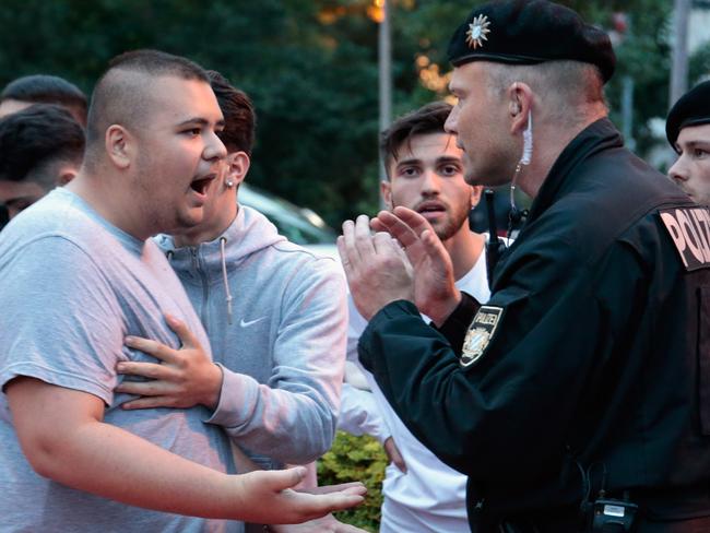 Riot police try to calm down teenage mourners near the crime scene at OEZ shopping centre, the day after the shooting spree.