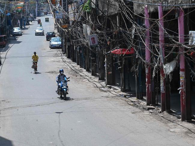 Motorists make their way through a partially deserted closed market during a lockdown imposed as a preventive measure to curb the spread of the Covid-19 coronavirus in New Delhi on June 5, 2021. (Photo by Prakash SINGH / AFP)