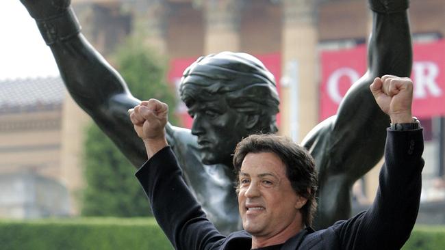 Sylvester Stallone poses in front of the bronze statue of Rocky Balboa.