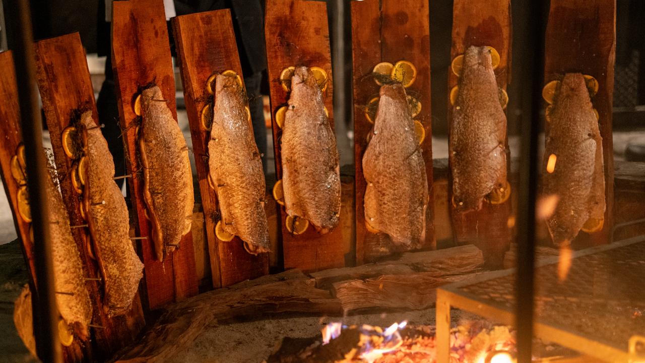 Barramundi cooking on vertical wooden planks around a giant fire pit at the Shelter Pererenan restaurant in Bali. Picture: @shelterpererenan