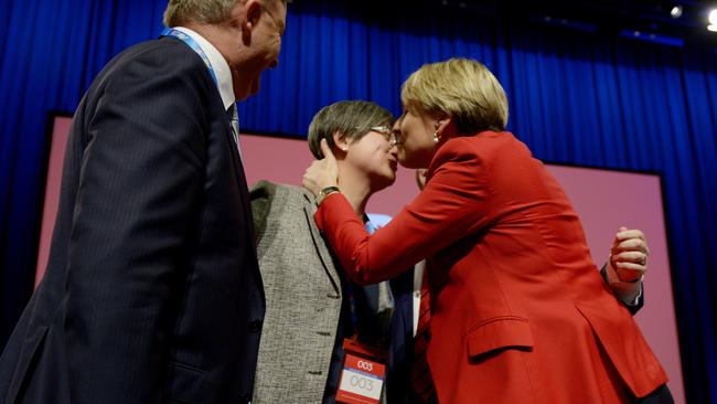 Senator Penny Wong (left) is kissed by deputy opposition leader Tanya Plibersek (right) after a successful vote on the same sex marriage bill.