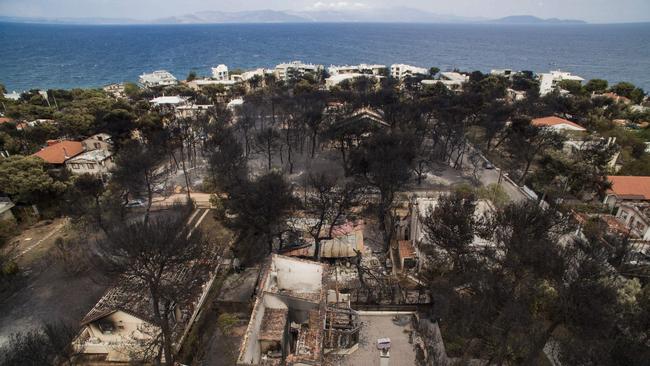 An aerial view shows burnt houses following a wildfire in the village of Mati, near Athens, on July 24, 2018.  Raging wildfires killed 60 people in Greece, devouring homes and forests as terrified residents fled to the sea to escape the flames, authorities said on July 24, 2018. Orange flames engulfed pine forests, turning them to ash and leaving lines of charred cars in the smoke-filled streets of seaside towns near Athens.  / AFP PHOTO / SAVVAS KARMANIOLAS