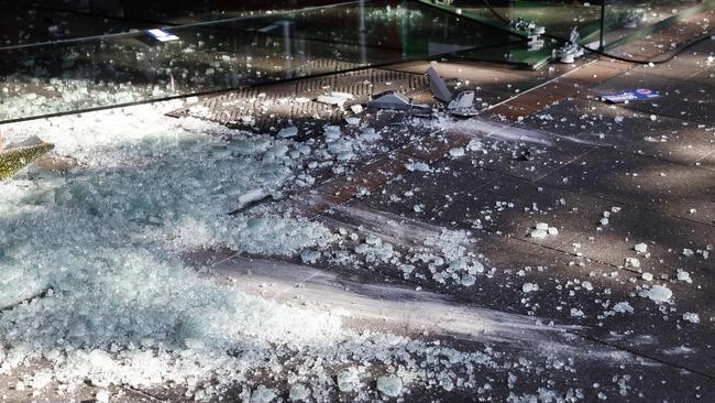 Smashed glass litters the footpath outside the shop. Picture: Richard Dobson