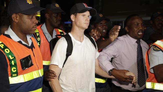 Steve Smith is escorted by police officers through Johannesburg airport.