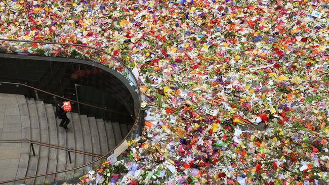 The floral tribute at Martin Place continues to expand on day 3 with members of the public pouring into the area to lay flowers as a mark of respect for those killed and were involved in the siege on Monday. An office worker walks down a set of stairs the leads underneath Martin Place. Picture: Toby Zerna