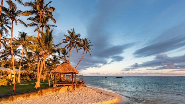 The sun sets over a beach hut surrounded by palm trees at Viti Levu, Fiji. Picture: File