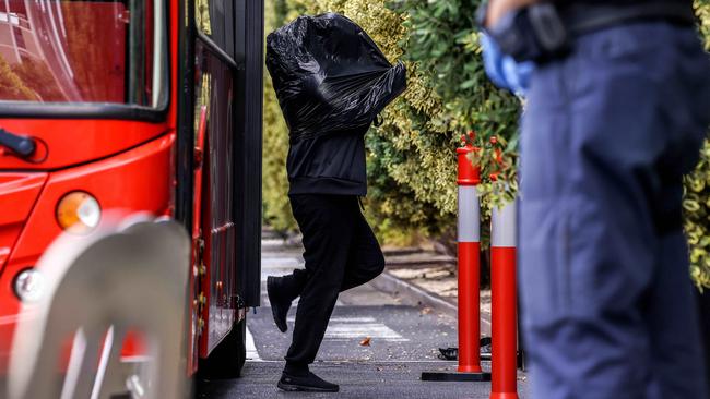 A person from Melbourne’s CBD wears a garbage bag during their transfer to the Pullman Hotel in Albert Park. Picture: NCA NewsWire / Ian Currie