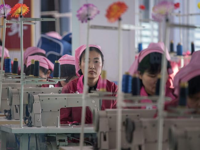 A woman looks up from a sewing machine in a workroom at the Pyongyang Bag Factory in Pyongyang. Picture: Ed Jones/AFP.