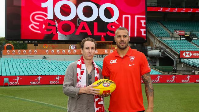 Swans fan Alex Wheeler (left) returns the match ball to Lance Franklin that he kicked to bring up his 1000-goal milestone. Picture: Gaye Gerard