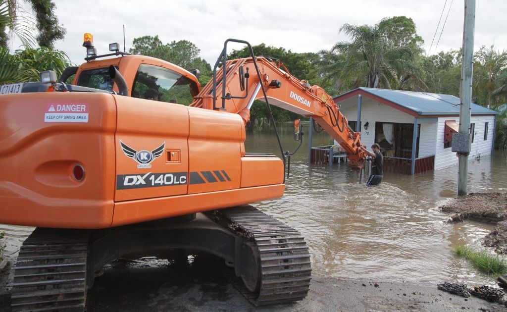 A 12 tonne excavator moves units to higher ground as the Mary River rises. . Picture: Robyne Cuerel