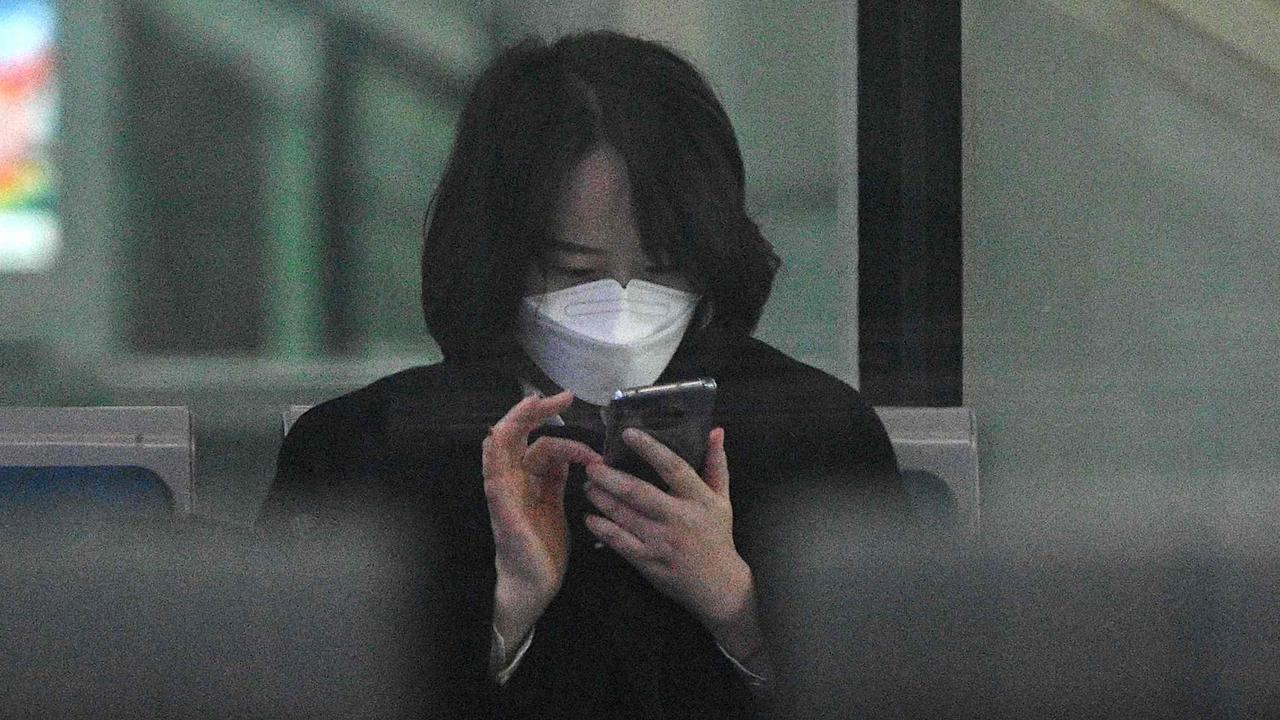 Wearing a face mask is one precaution people are taking to prevent the spread of coronavirus, but your phone could be harbouring scores of bacteria. Picture: Noel Celis / AFP