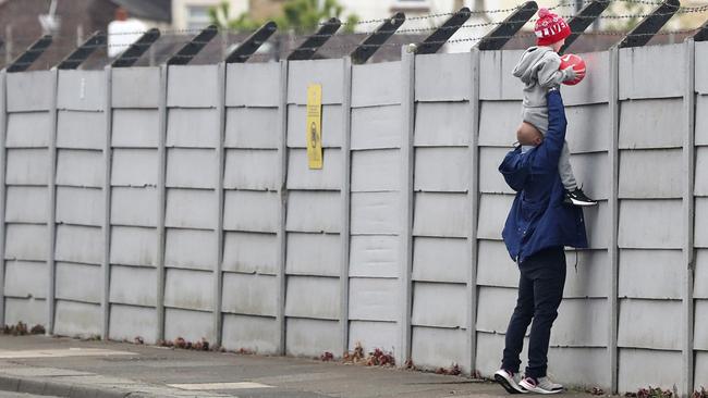A man holds his child up over a fence to look into Liverpool's training session