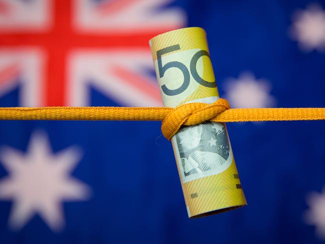 Studio shot close up of an Australian dollar note tied in a knot with the Australian flag as a background. No people.