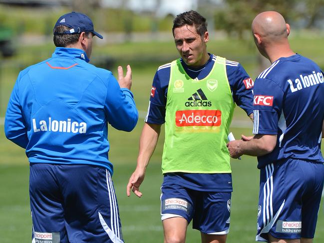 Ange Postecoglou and Kevin Muscat talk to Mark Milligan during a Melbourne Victory training session.