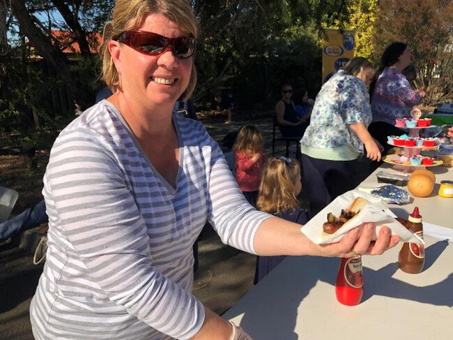 A voluneer serving a sausage sandwich.