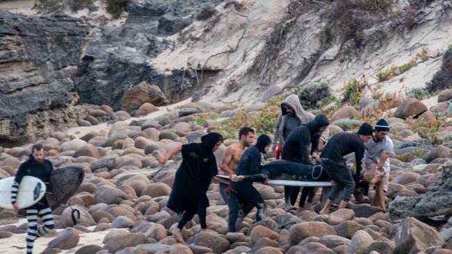 Fellow surfers carry Alejandro Travaglini to medical aid. Picture: Peter Jovic