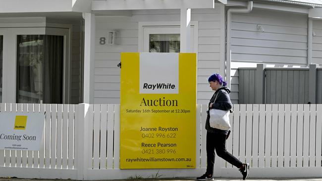 A woman walks past an auction sign outside a house in Melbourne. Picture: William West/ AFP.