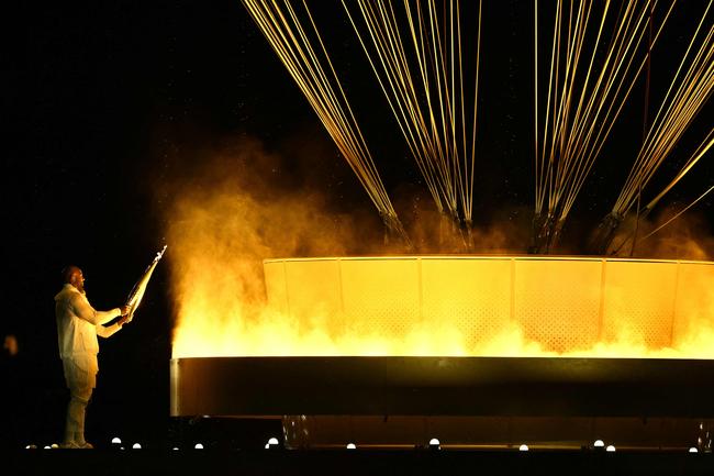 France's torchbearers judoka Teddy Riner and sprinter Marie-Jo Perec light the Olympic cauldron during the opening ceremony of the Paris 2024 Olympic Games in Paris on July 26, 2024. (Photo by Ben STANSALL / AFP)