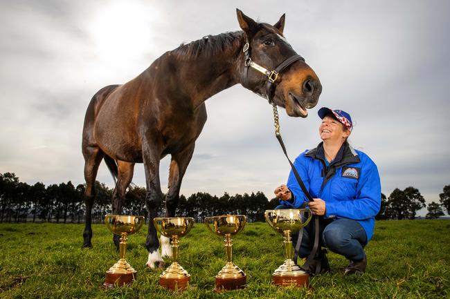 Makybe Diva pictured at her home west of Geelong with her strapper Natalie Hinchcliffe, her three Melbourne Cup trophies and the 2022 Lexus Melbourne Cup trophy. Picture: Mark Stewart