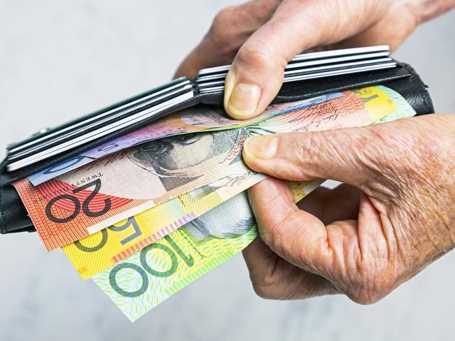 Close-up, senior female hands taking Australian banknotes (cash, currency) from purse containing many credit cards.  Horizontal, studio, copy space. . Picture: iStock