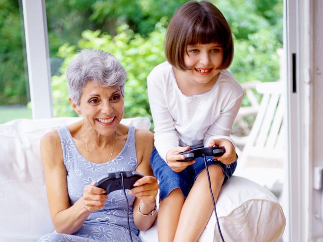 View of a girl (8-10) playing a video game with her grandmother. Generic image.