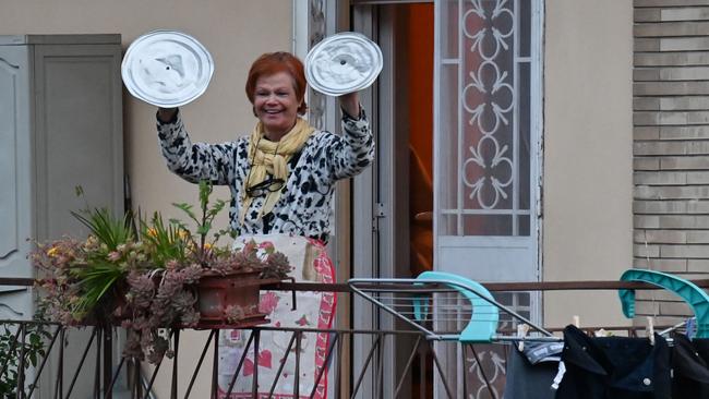 With Italy in lockdown a resident uses pot lids to play cymbals as she takes part in a music flash mob called "Look out from the window”. Picture: Andreas Solaro/AFP