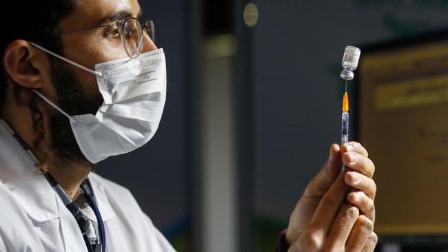 An Israeli healthcare worker prepares a dose of the COVID-19 vaccine for people queuing at the Kupat Holim Clalit clinic in Jerusalem, on January 14. Picture: Ahmad Gharabli / AFP)