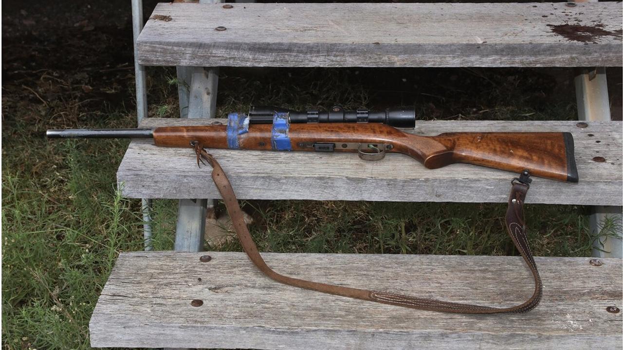 A rifle located on the steps of the Train house with blood splatter on the step.