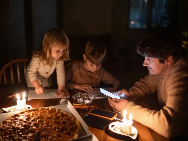 Family sitting at home with candles during blackout.