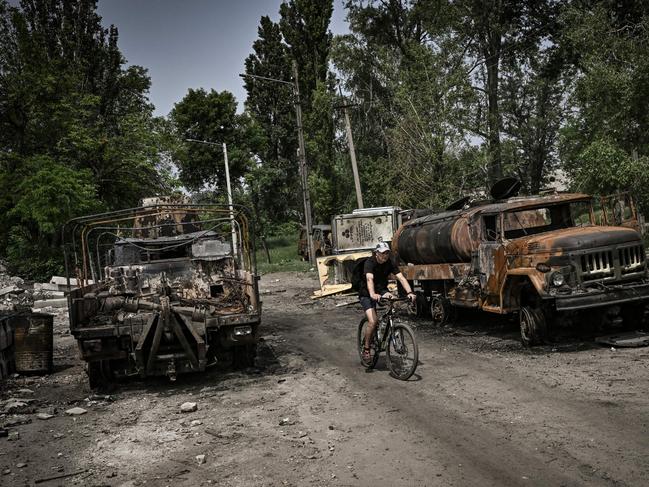 A man rides his bicycle between two destroyed military trucks in the city of Lysychansk, eastern Ukrainian region of Donbas. Picture: AFP