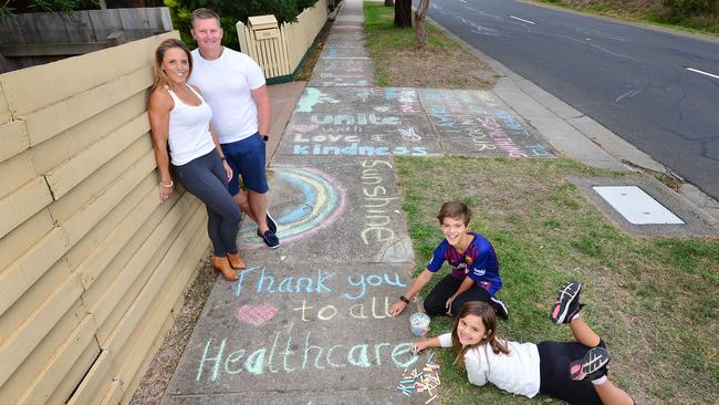 Families around Melbourne did what they could to cope with lockdown. Alannah and Hugh of Langwarrin write messages of hope and draw pictures in coloured chalk on the footpath outside their house with their mum Kendal and Ty, her partner. Picture: Nicki Connolly