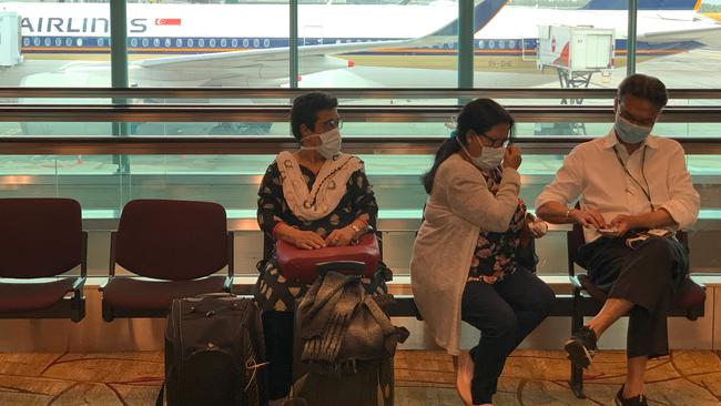 Passengers wearing protective masks wait for their flight at Changi International Airport in Singapore on February 19.