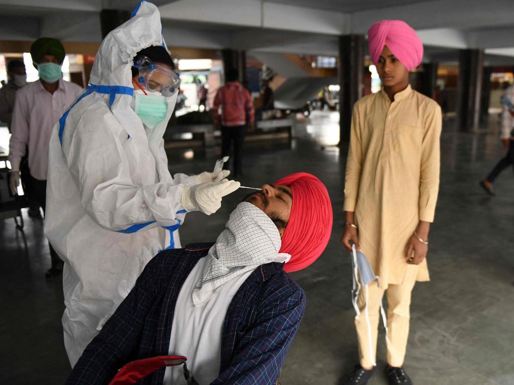 A health worker collects swab samples from the passengers for the COVID-19 coronavirus screening at a bus terminal in Amritsar, India. Picture: AFP