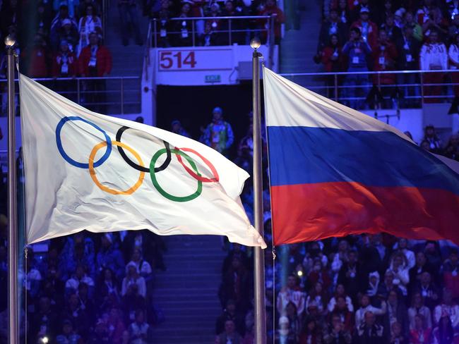 (FILES) In this file photo taken on February 23, 2014 The Olympic flag (L) and the Russian flag flutter during the Closing Ceremony of the Sochi Winter Olympics at the Fisht Olympic Stadium. - The World Anti-Doping Agency (WADA) decided on December 9, 2019, to exclude Russia from the Olympic Games for four years, including Tokyo-2020 and Beijing-2022, to sanction the falsification of test data submitted to the agency, a WADA spokesman said after the Executive Committee meeting in Lausanne. (Photo by Damien MEYER / AFP)