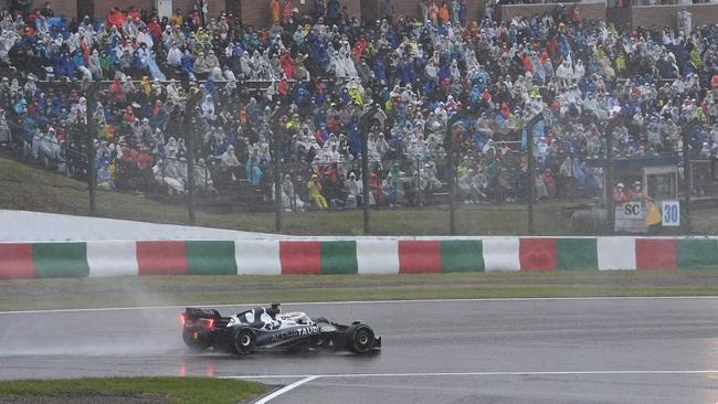 AlphaTauri's French driver Pierre Gasly travels past fans during a rainstorm at the Formula One Japanese Grand Prix at Suzuka, Mie prefecture on October 9, 2022. (Photo by Philip FONG / AFP)