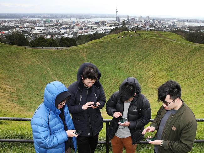 AUCKLAND, NEW ZEALAND - JULY 13: Zijia Ge (L) Jack Zheng (CL) Ky Pham (CR) and Tony Sun (R) search for Pokemon on the top of Mount Eden on July 13, 2016 in Auckland, New Zealand. The augmented reality app requires players to look for Pokemon in their immediate surroundings with the use of GPS and internet services turning the whole world into a Pokemon region map. The hugely popular app has seen Nintendo shares soar following its limited release in the U.S., Australia and New Zealand on July 6. (Photo by Fiona Goodall/Getty Images)