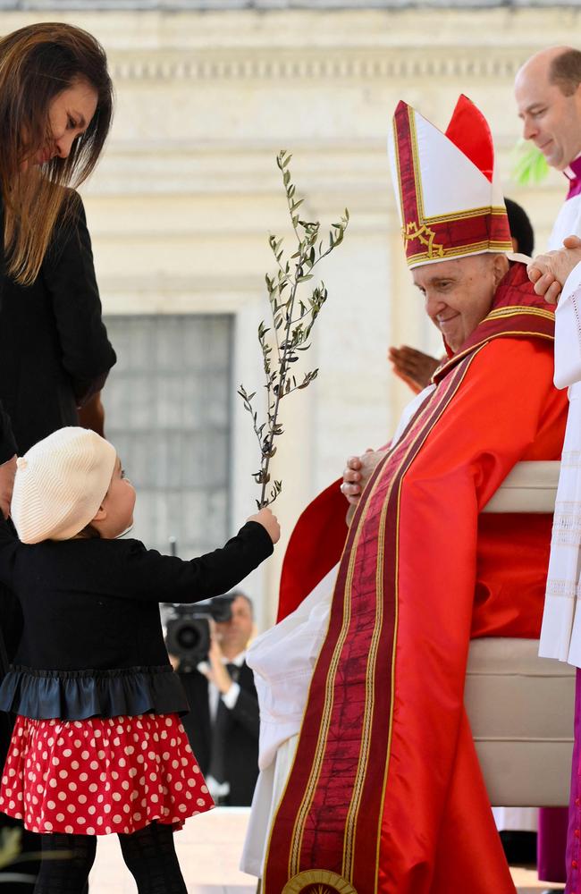 A girl handing an olive branch to Pope Francis during the Palm Sunday mass at St. Peter's Picture: Handout / VATICAN MEDIA / AFP