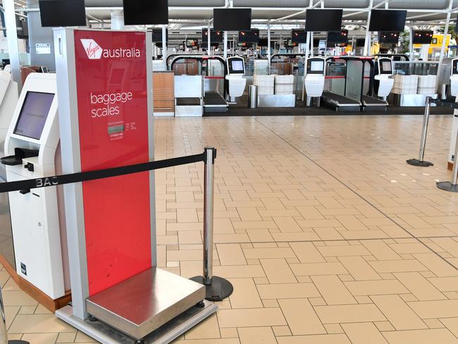 Empty Virgin Australia check-in counters are seen at Brisbane International Airport in Brisbane, Friday, April 17, 2020. The Australian government has forced airline carriers to cut both their domestic and international flights in order to slow the spread of the coronavirus (COVID-19) disease. (AAP Image/Darren England) NO ARCHIVING