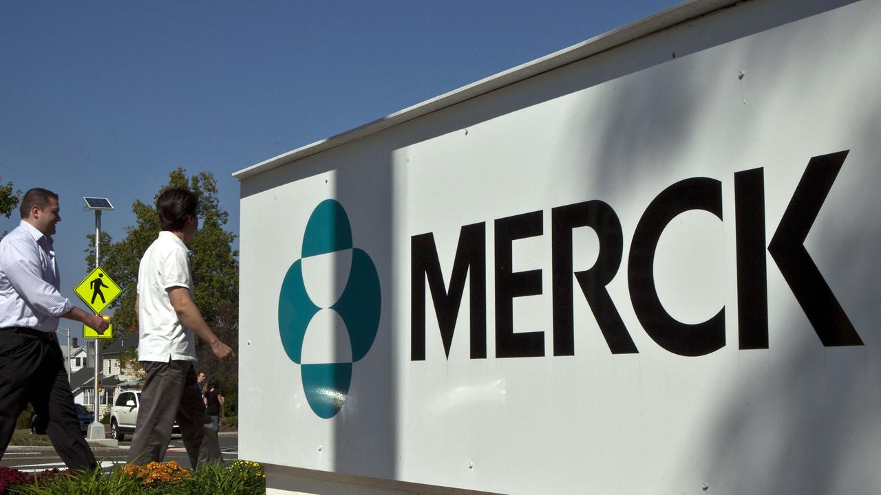 Pharmaceutical company Merck employees walk past a Merck sign in front of the company's building in Summit, New Jersey.