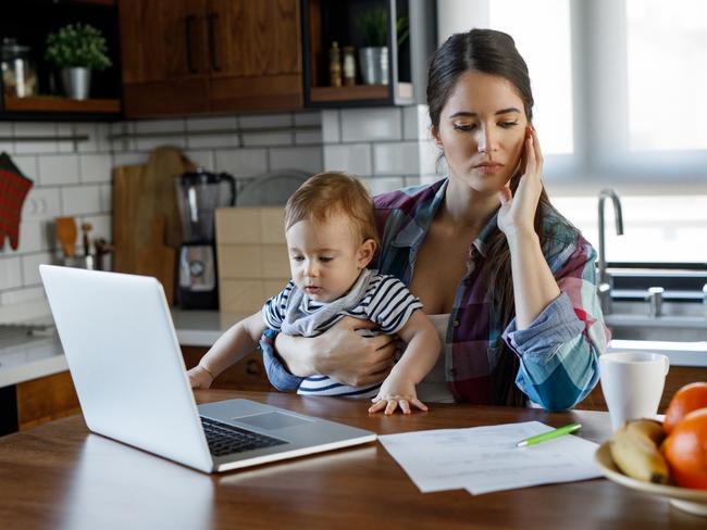 CORONAVIRUS:  A young mother multitasking. She is working from home and looking after her toddler at the same time