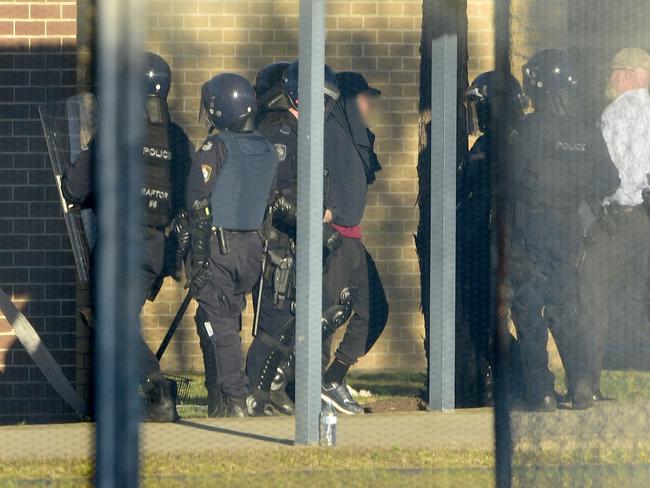 Riot police lead a detainee away in handcuffs after a riot at the Frank Baxter Juvenile Justice Centre, which came after the June “disturbance”. (AAP Image/Bianca De Marchi)