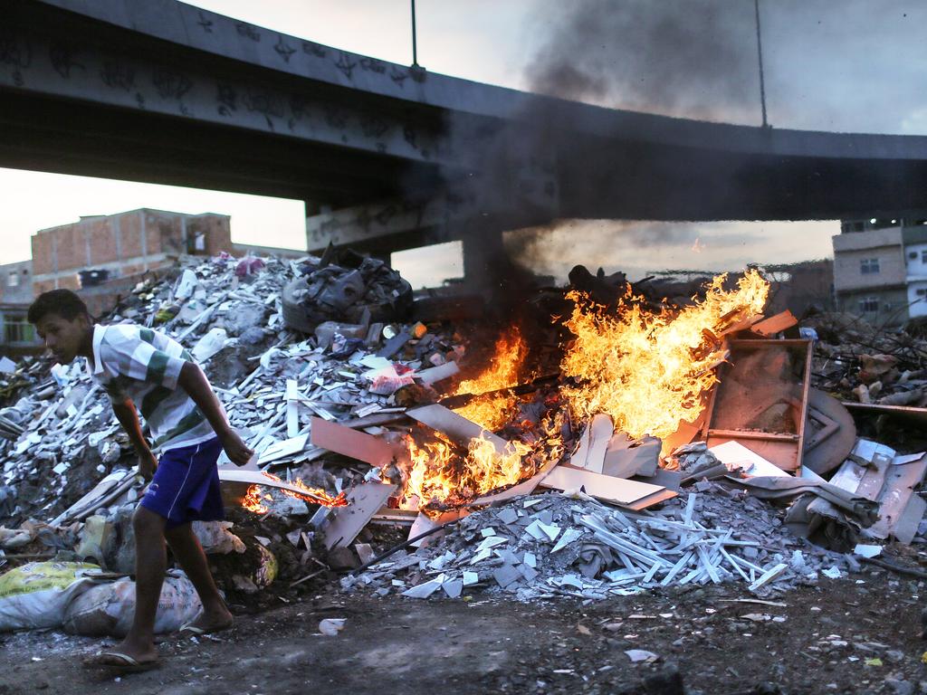 Trash is burned in an area where garbage is dumped near the main highway linking Rio’s international airport to the city in the Mare favela community complex on July 18, 2016 in Rio de Janeiro, Brazil. The Mare complex is one of the largest favela complexes in Rio and is challenged by violence, pollution and poverty. The Rio 2016 Olympic Games begin August 5. (Photo by Mario Tama/Getty Images)