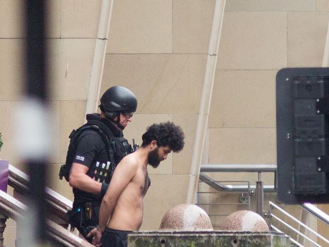 A police officer escorts a man from the Park Inn Hotel as police attend the scene of a fatal stabbing incident at the Park Inn Hotel. Picture: AFP