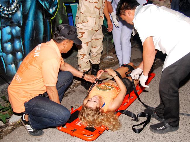 Rescue workers help an unidentified woman after a bomb blast in the southern resort city of Hua Hin. Picture: Daily News via AP.