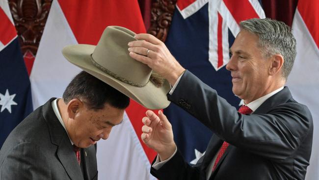 Indonesia Defence Minister Sjafrie Sjamsoeddin receives an Australian hat as a gift from Richard Marles. Picture: AFP