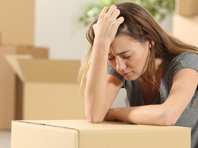 Sad homeowner moving home after eviction sitting on the floor of the living room at home