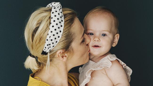 Young mother, holding her newborn baby boy at home in living room, back lit